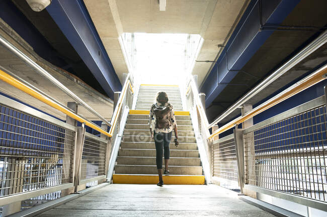 Empresária com mochila andando em passos na estação de metrô — Fotografia de Stock