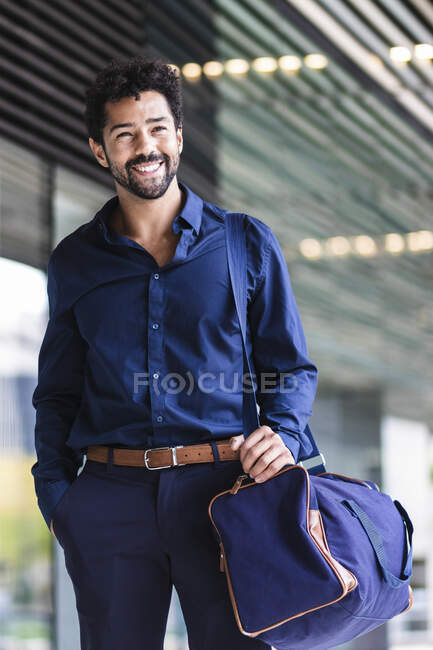 Imprenditore sorridente con borsa in piedi in città — Foto stock