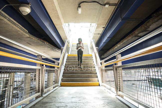 Businesswoman using mobile phone while walking on staircase in subway station — Stock Photo