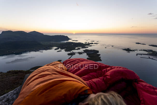 Мандрівник лежить у спальному мішку проти моря у Воландстіндені (Лофотен, Норвегія). — стокове фото