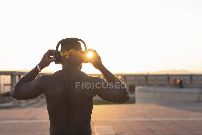 Sportif musclé portant un casque pendant qu'il est debout au parc pendant le coucher du soleil — Photo de stock