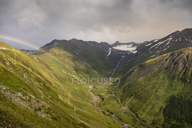 Rainbow and storm clouds over mountain and valley — Stock Photo