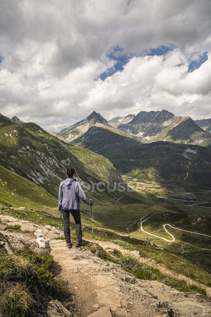 Женщина с собакой, стоящей в ландшафте, глядя на горный перевал — стоковое фото