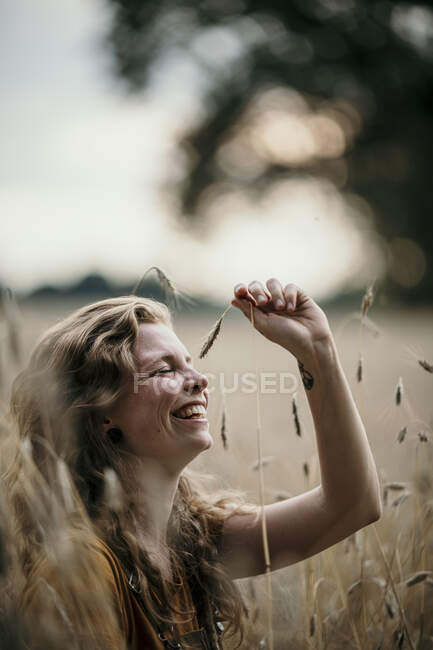 Жінка посміхається, граючи з врожаєм на сільськогосподарському полі — стокове фото