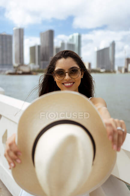 Усміхнена жінка з капелюхом, стоячи в місті. — стокове фото