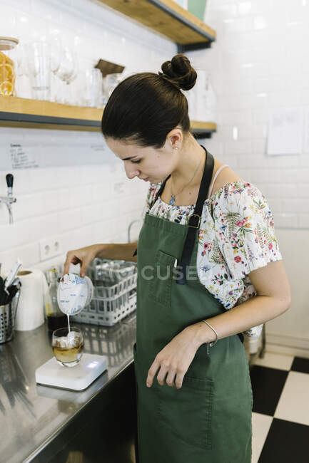 Barista vertiendo leche en el café mientras está de pie en la cocina en la cafetería - foto de stock