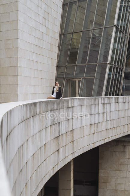Empreendedora mulher sentada no muro de contenção do prédio de escritórios — Fotografia de Stock