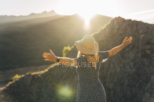 Woman with arms raised standing in front of mountain on sunny day — Stock Photo