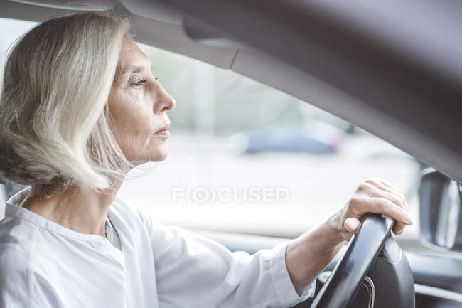 Mulher de negócios madura com cabelo branco curto carro de condução na cidade — Fotografia de Stock
