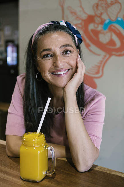 Посмішка жінка сидить з свіжим соком за прилавком у кафе. — стокове фото