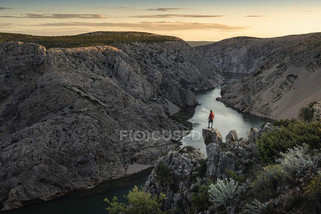 L'uomo in piedi sulle rocce e guardando il fiume nel canyon al tramonto — Foto stock
