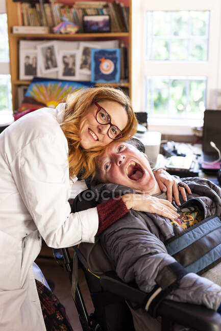 Infirmière embrassant un homme handicapé assis au centre de réadaptation — Photo de stock
