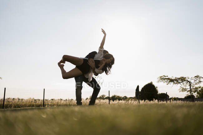 Ballerino maschio raccogliendo ballerina mentre balla in campo contro il cielo limpido — Foto stock