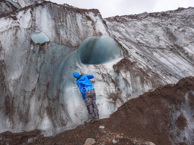 Hombre adulto medio examinando glaciar mientras está de pie en la cresta de la montaña de Svinafellsjokull, Islandia - foto de stock