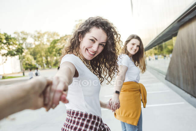 Усміхаючись, дівчата тримаються за руки під час прогулянки в парку. — стокове фото