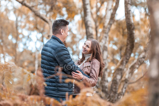 Casal romântico abraçando enquanto está em pé no parque durante o outono — Fotografia de Stock