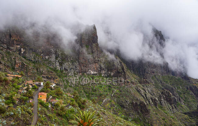 Spain, Province of Santa Cruz de Tenerife, Masca, Low clouds floating over secluded village in Macizo de Teno range — Stock Photo