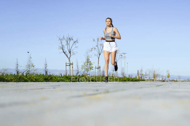 Молодой спортсмен бежит по тропинке против неба — стоковое фото