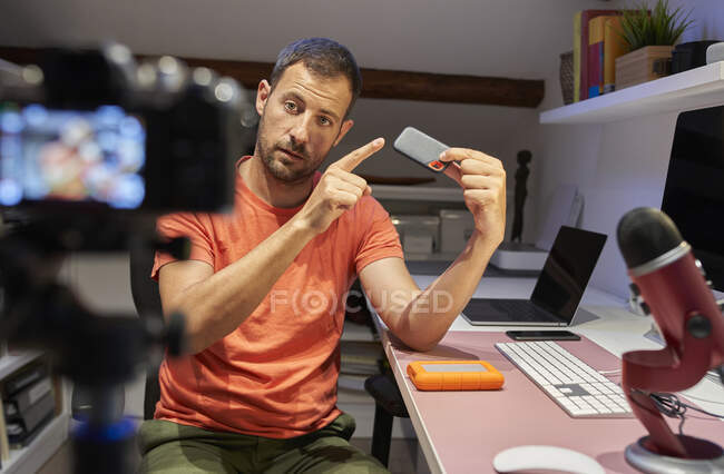 Metà uomo adulto che punta disco rigido esterno mentre la registrazione video sulla fotocamera a casa — Foto stock