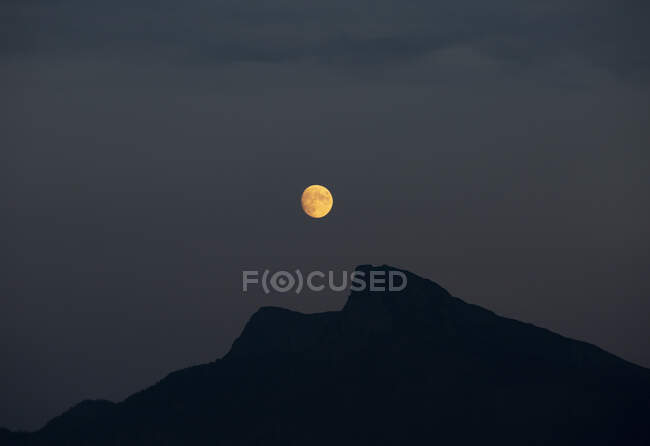 Luna piena incandescente sulla silhouette della montagna Schafberg di notte — Foto stock