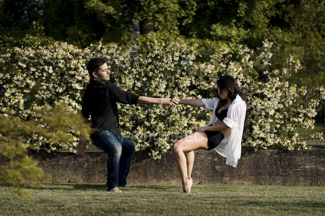Heterosexual couple dancing while holding hand over grass in back yard — Stock Photo