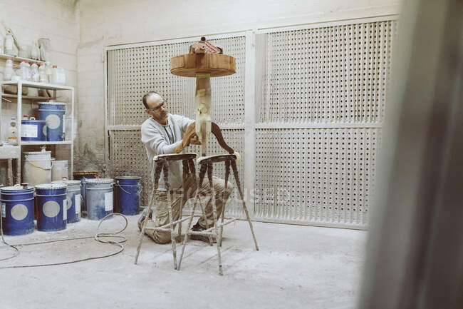 Mesa de pulir artesano mientras se arrodilla en el taller - foto de stock