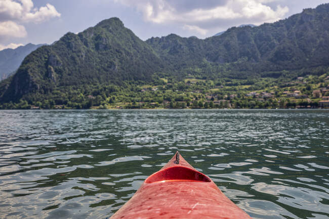 Kayak boat floating on Lake Idro in front of mountains — Stock Photo