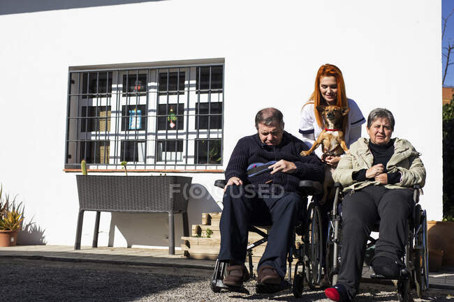 Femme handicapée et homme avec infirmière tenant le chien à l'extérieur du centre de réadaptation — Photo de stock