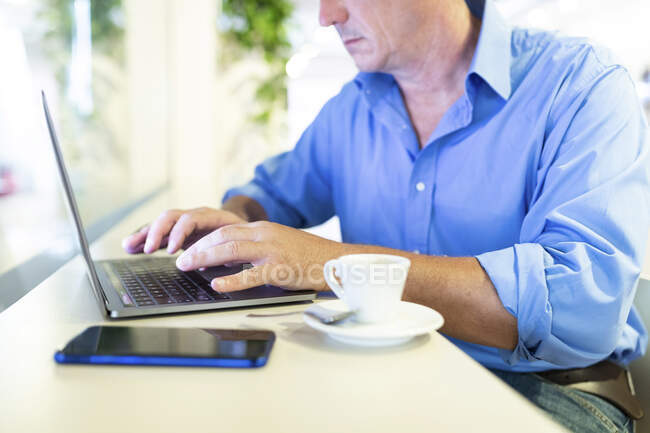 Businessman using laptop while sitting with coffee at cafe — Stock Photo