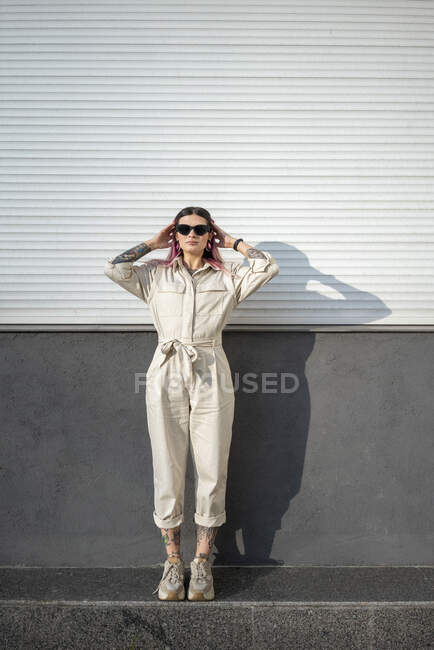 Стильная молодая женщина в солнцезащитных очках на стене в солнечный день — стоковое фото