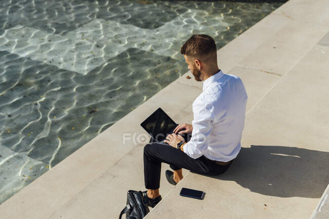 Homme d'affaires adulte moyen travaillant sur tablette numérique tout en étant assis sur les marches — Photo de stock