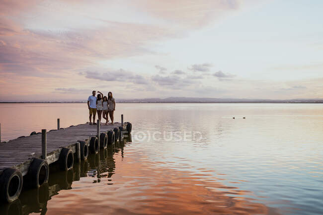 Family standing at jetty against sky during sunset — Stock Photo