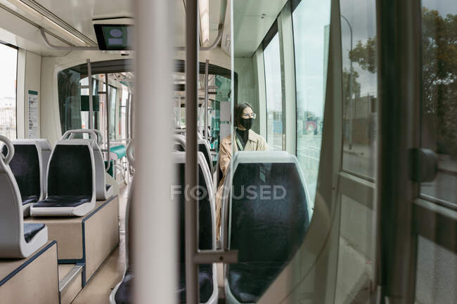 Donna che indossa maschera facciale in viaggio mentre seduto in tram — Foto stock