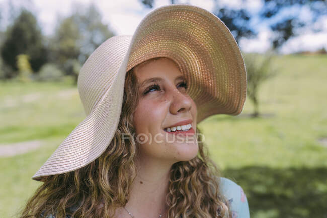 Mujer joven reflexiva con sombrero de sol durante el día soleado en el parque - foto de stock