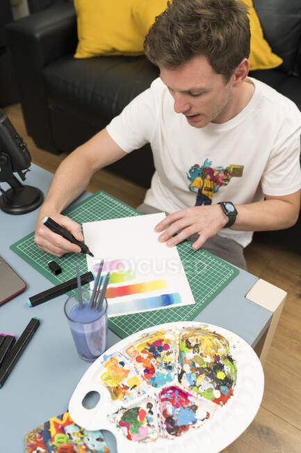 Artiste masculin montrant le dégradé de couleur à travers un stylo à coloration tout en streaming en direct à la maison — Photo de stock