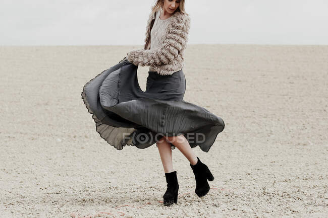 Frau im Rock tanzt am Strand gegen den Himmel — Stockfoto