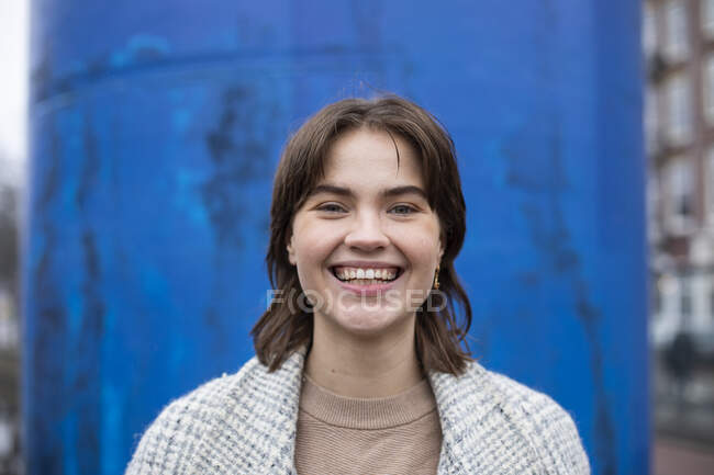 Belle femme souriante contre la structure bleue — Photo de stock