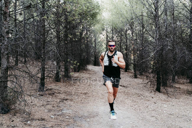 Jovem desportista masculino correndo na estrada de terra da montanha — Fotografia de Stock