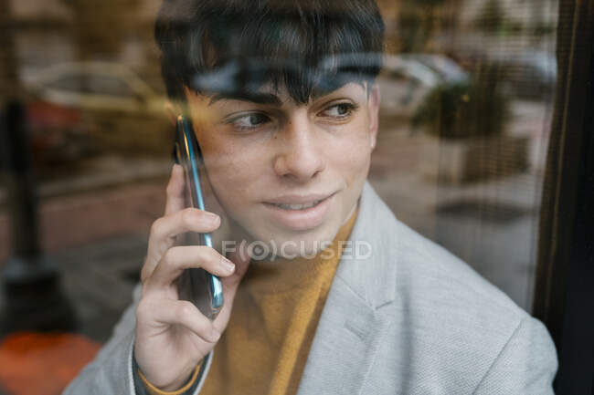 Чоловік розмовляє по мобільному, дивлячись у вікно на кафе. — стокове фото