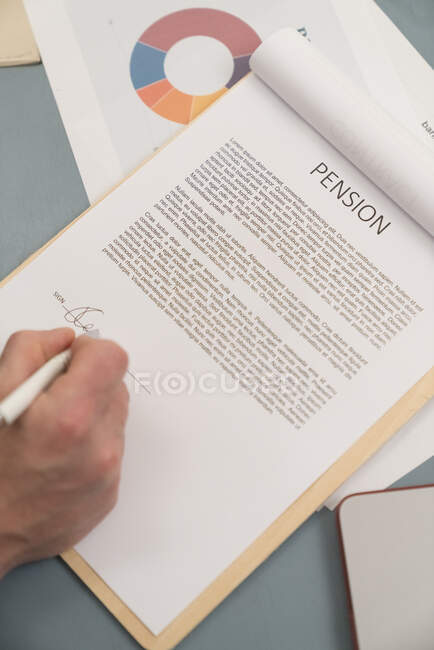 Бизнесмен подписывает пенсионные бумаги на столе дома — стоковое фото