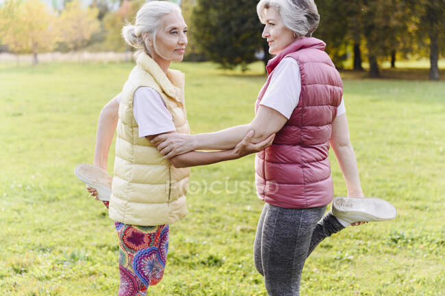 Maturo femmina amici fare warm up esercizio insieme a pubblico parco — Foto stock