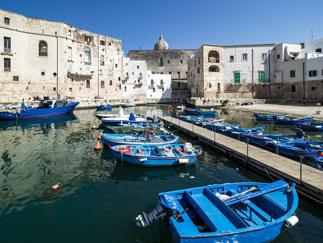 Barca blu ormeggiata in canale da edifici nella giornata di sole a Monopoli, Puglia, Italia — Foto stock