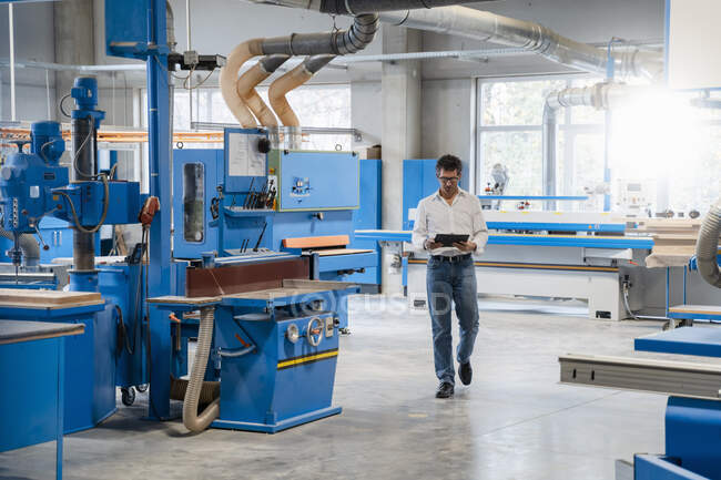 Charpentier marchant autour du hall de production avec presse-papiers dans les mains — Photo de stock