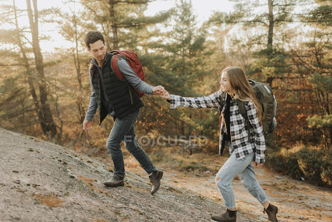 Молода пара тримається за руки, коли піднімається на гору восени. — стокове фото