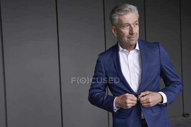 Businessman wearing suit looking away while standing against wall — Stock Photo