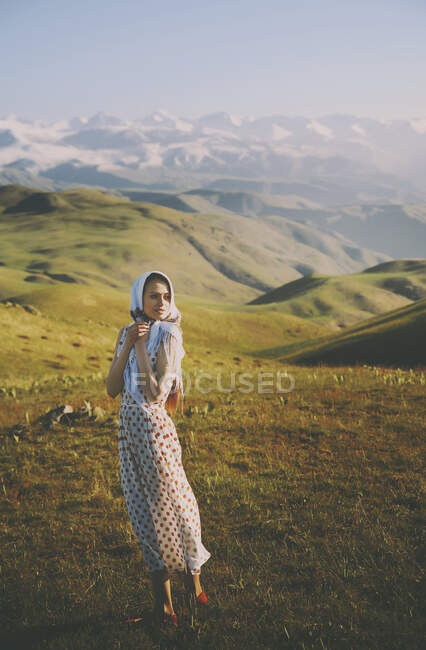 Young woman with polka dot dress standing against mountains — Stock Photo