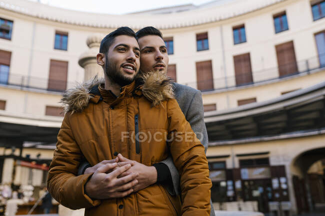 Young man embracing male friend while standing in city — Stock Photo