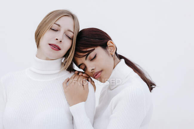 Young women with eyes closed against white background - foto de stock