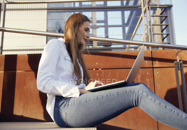 Jovem empresária trabalhando no laptop enquanto se senta em passos — Fotografia de Stock