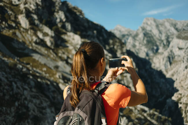 Caminante tomando fotos a través del teléfono móvil mientras está de pie en Cares Trail en el Parque Nacional Picos De Europe, Asturias, España - foto de stock